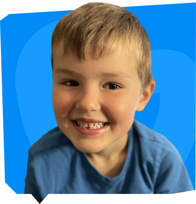 A smiling child with short hair, wearing a blue shirt, against a bright blue background.