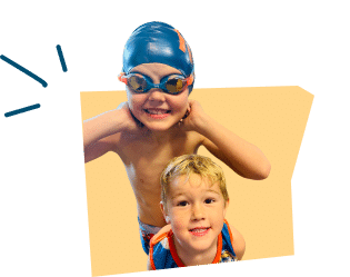 Two young boys are smiling in a swimming area; one is wearing a swim cap and goggles, while the other is in a swimsuit.